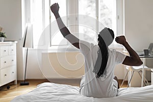 Rear View Of African American Man Stretching In Bed In The Morning