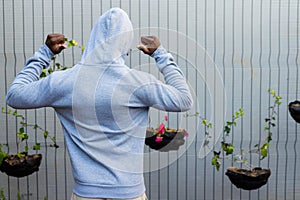 Rear view of african american man wearing grey hooded sweatshirt against white fence, copy space