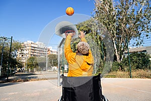 Rear view of African American man in a wheelchair throwing basketball in court playing alone.