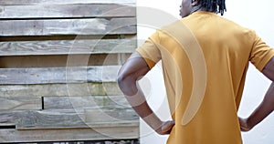 Rear view of african american man in yellow t shirt, with hands on hips, slow motion, copy space