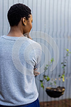 Rear view of african american woman in grey sweatshirt against white fence, copy space