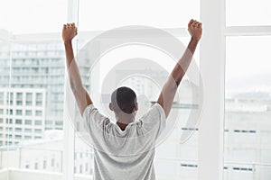 Rear view of Afro man stretching his arms near window