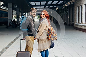 Rear view of amorous hipster couple walking down station and chatting outdoors. Holyday concept