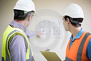 Rear View Of Architect On Site Discussing Plans With Builder