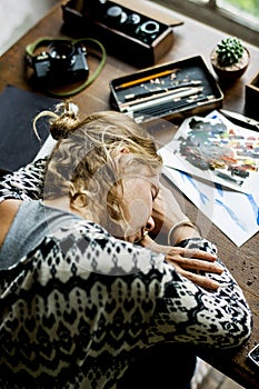 Rear view of artist woman taking a nap on work table