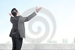 Rear view of Asian businessman standing with raised hand on the rooftop