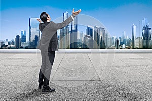 Rear view of Asian businessman standing with raised hand on the rooftop