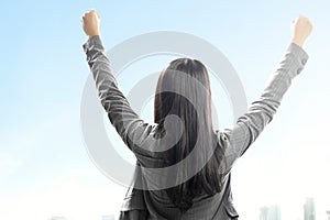 Rear view of Asian businesswoman standing with raised hand on the rooftop