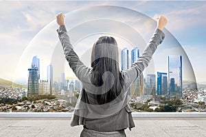 Rear view of Asian businesswoman standing with raised hand on the rooftop