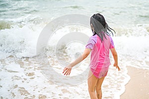 Rear View of Asian Child on Sea Beach with Ocean Wave