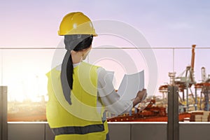 Rear view of an Asian construction worker with hardhat holding planning paper