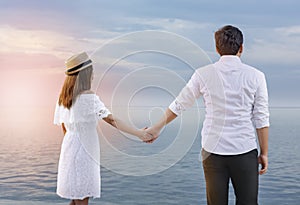 Rear view of asian romantic couple holding hands together on the beach