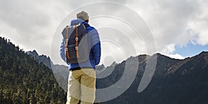 Rear view of asian traveler with backpack looking at mountains