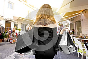 Rear view of an Asian woman holding shopping bags in the city