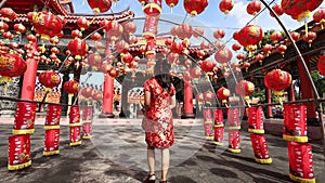 Rear view of Asian woman in red cheongsam qipao dress is visiting the Chinese Buddhist temple during lunar new year for traditiona