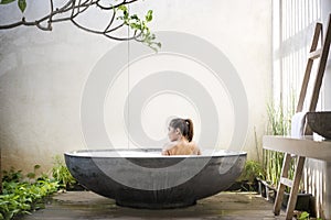 Rear view of asian woman relaxing in the bathtub