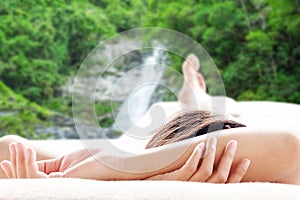 Rear view of asian woman relaxing on a sofa at the waterfall