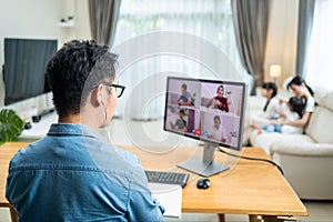 Rear view of Asian Working business man father talk to colleagues team on virtual video call conference online. Male freelance wor
