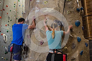 Rear view of athletes rock climbing in studio