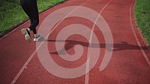 Rear view of athletic woman running on track stadium at summer