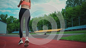 Rear view of athletic woman running on track stadium at summer