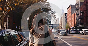 Rear view of attractive brunette female walking around urban autumnal streets of NYC lit by sunlight