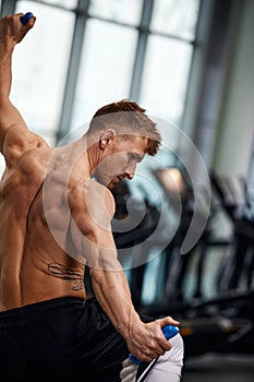 Rear view of Attractive young fit and toned sportswoman working out with battle ropes. Motion blur