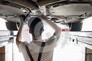 Rear view of automobile mechanic examining car in workshop