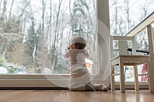 Rear view of baby girl kneeling by the dirty glass door