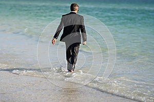 Rear view of back business man in suit in sea water at beach. Freelancer on summer sea beach. Business man in suit in