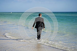 Rear view of back business man in suit in sea water at beach. Travel tourism and business concept. Crazy male office