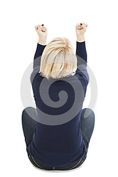 Rear view or back of a woman arms up, happy, sitting on floor. Isolated on white background.