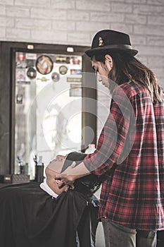 Rear view of barber man with long hair doing massage to the costumers with fresh towels