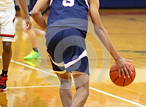 Rear view of basketball player dribbling the ball up court during a game