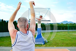 Rear view of a basketball player, shooting at basket outdoor