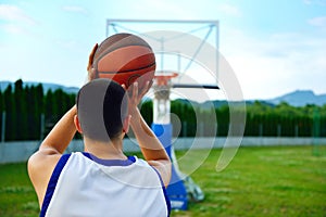 Rear view of a basketball player, shooting at basket outdoor