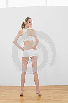Rear view of beautiful slender woman posing in sports hall