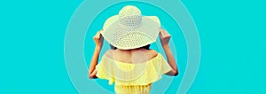 Rear view beautiful young woman model posing wearing a summer straw hat, dress on blue background