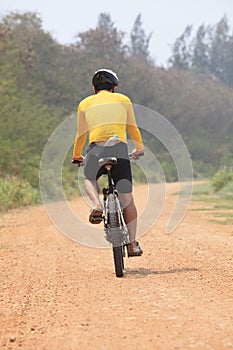 Rear view of bicycle man riding on dirt road with drinking water