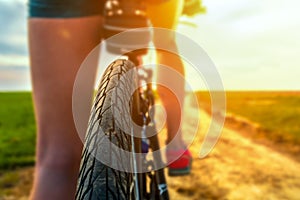 Rear view of a bicycle wheel on a country road at sunny day. Close up view of a bicycle protector. Cycling on a