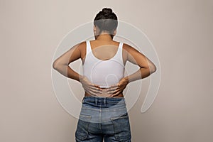 Rear view of black lady massaging her lower back