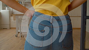 Rear view of black woman with weight problems trying to fit into tight jeans