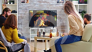 Rear view of blonde woman with her friends watching a tv show