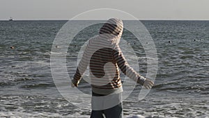 Rear view of a boy along the beach during daytime in Thailand. Creative. Boy child by the sea on a windy day.