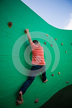 Rear view of boy climbing on green wall