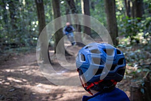 Rear view of a boy cycling in the forest wearing a helmet