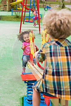 rear view of boy riding on rocking horse with smiling african american little kid