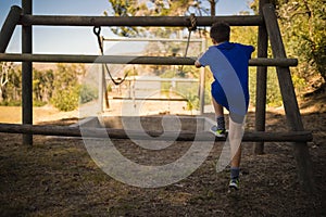 Rear view of boys climbing outdoor equipment during obstacle course