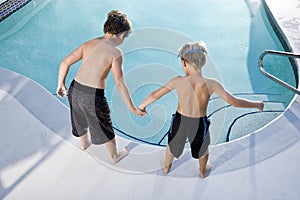 Rear view of boys looking in swimming pool