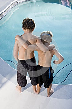 Rear view of boys looking in swimming pool